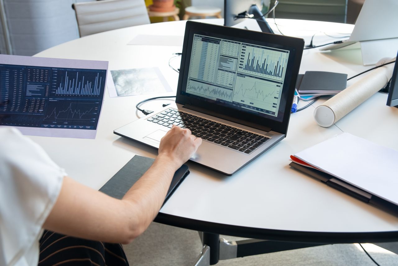 A desk with a laptop and printed charts, representing planning and budgeting an AI project